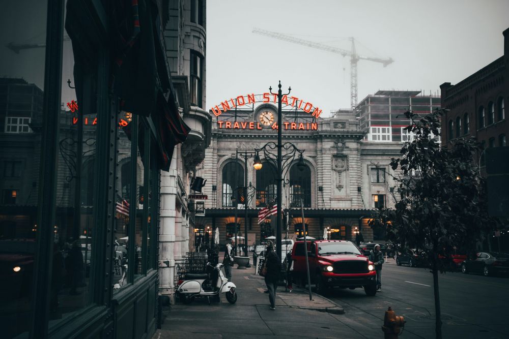 Foggy street view of Union Station with neon sign, cars, scooters, and construction cranes in the background.
